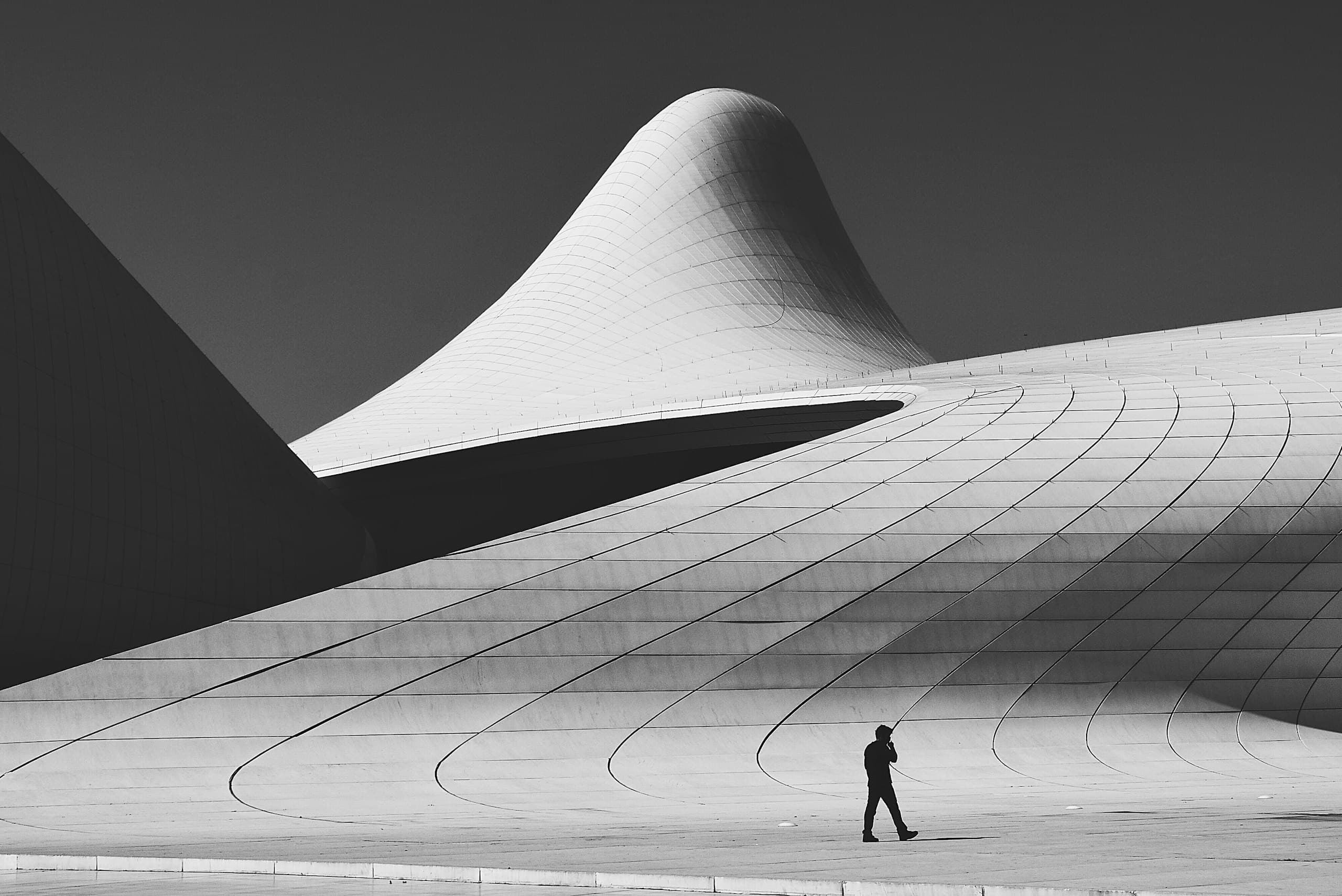 A sweeping concrete canopy crossed by a single figure