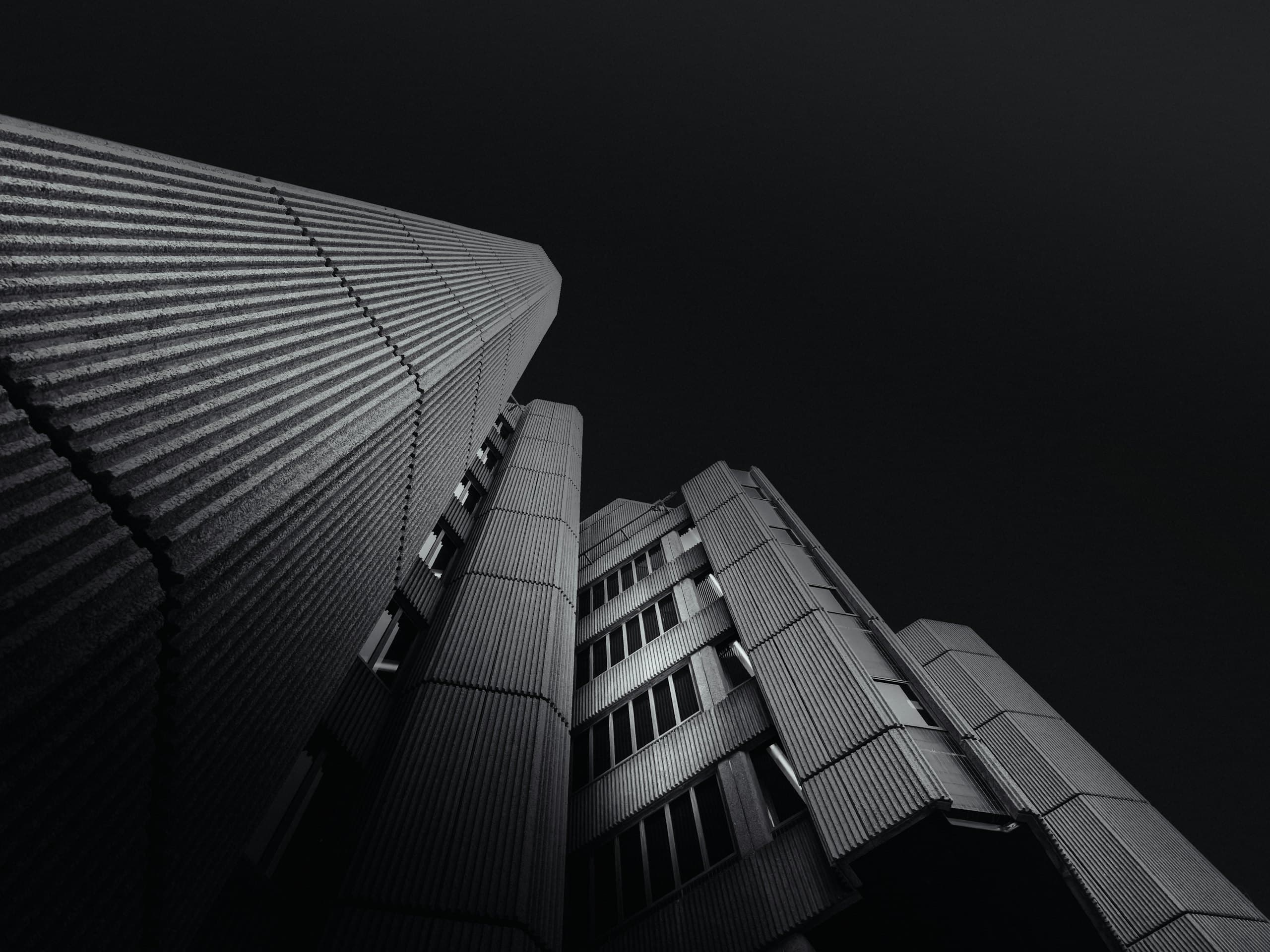 A dark contemporary tower seen from its base against an open sky